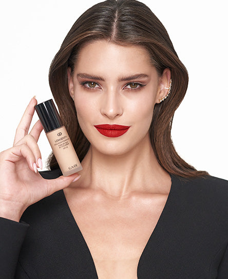 אישה מחזיקה בקבוק מייקאפ ונילון בגוון בהיר.